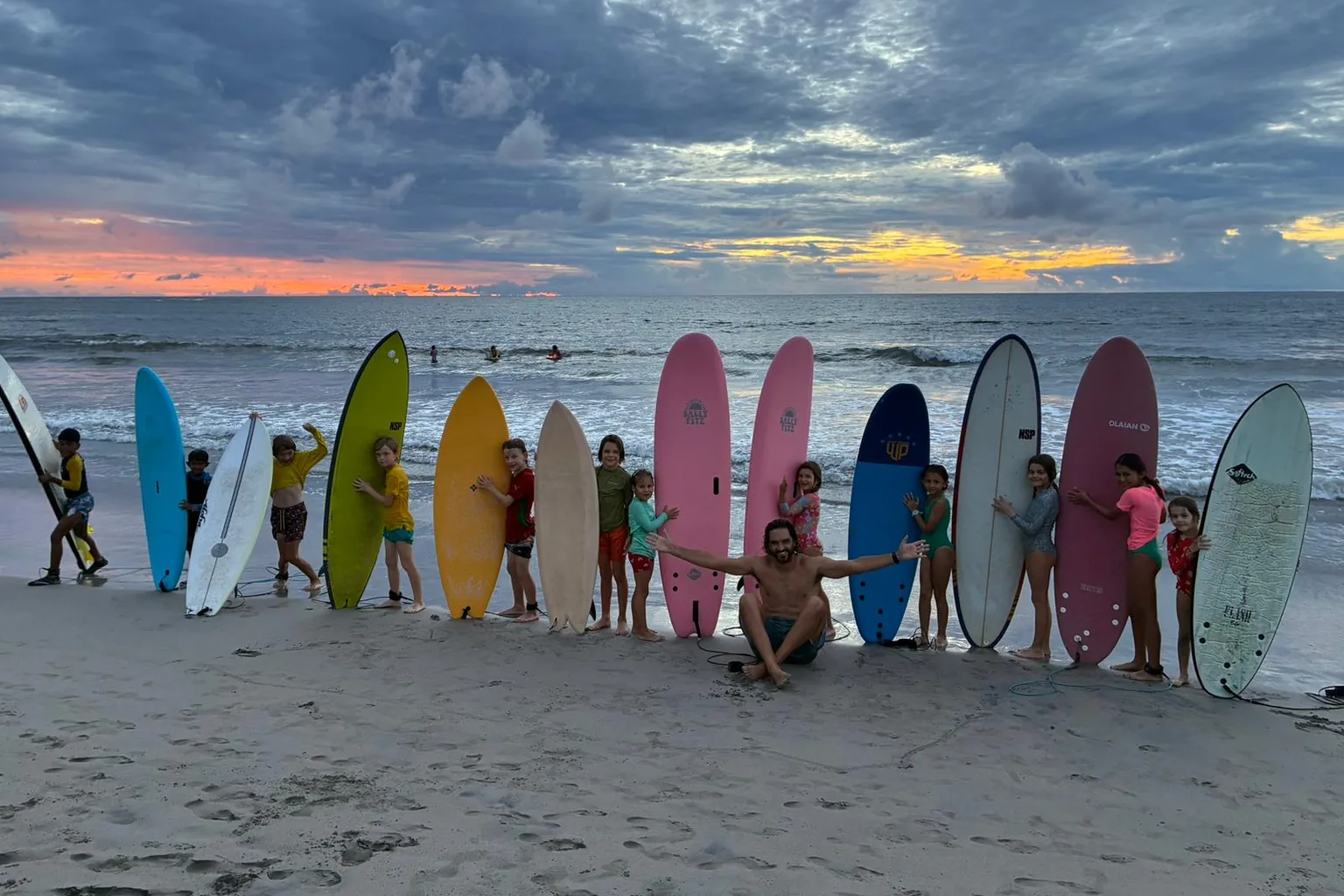 The whole club lined up behind their colourful surfboards on Tamarin beach at sunset.