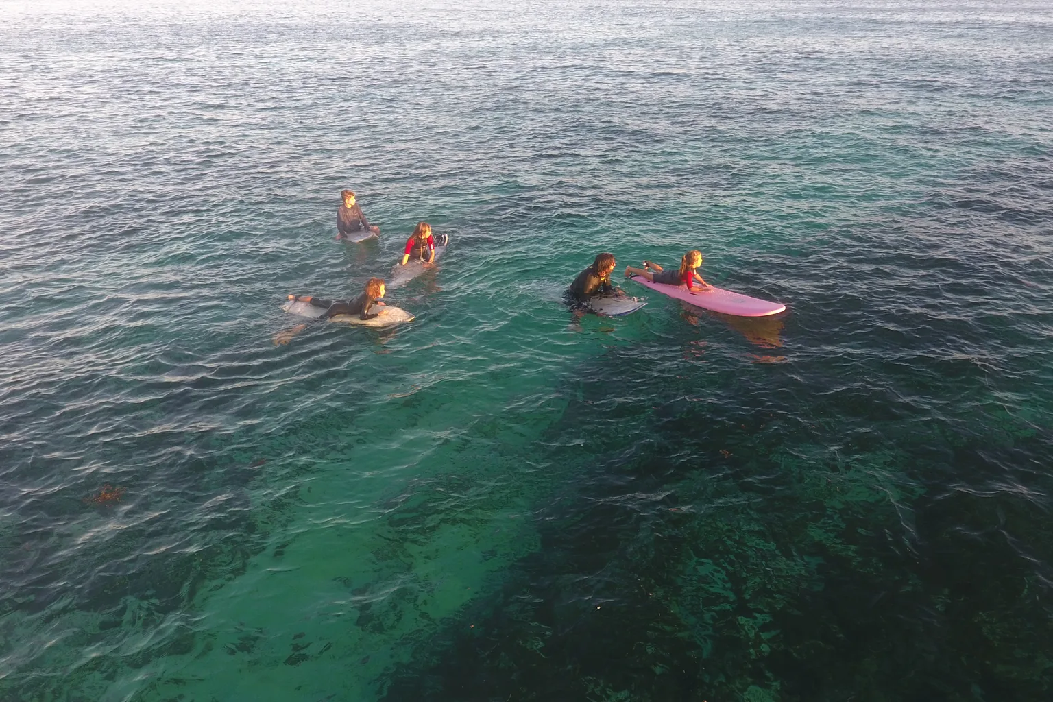 Drone view of Duckies and their coach sitting on boards over the turquoise Little Reef.