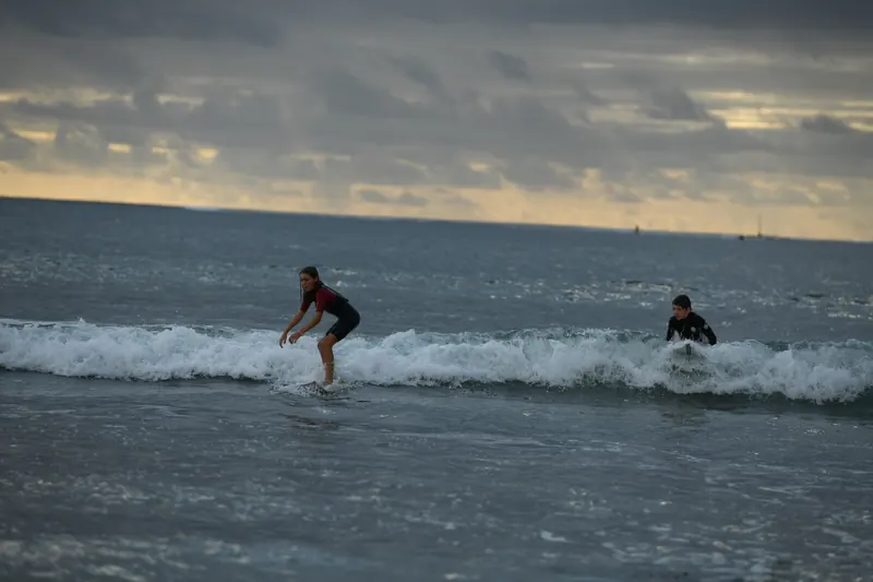 A finalist rides a wave under a golden evening sky.
