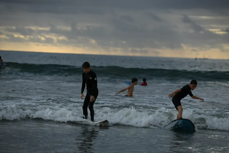 Two parents in wetsuits ride the same wave in the grey goose heat.