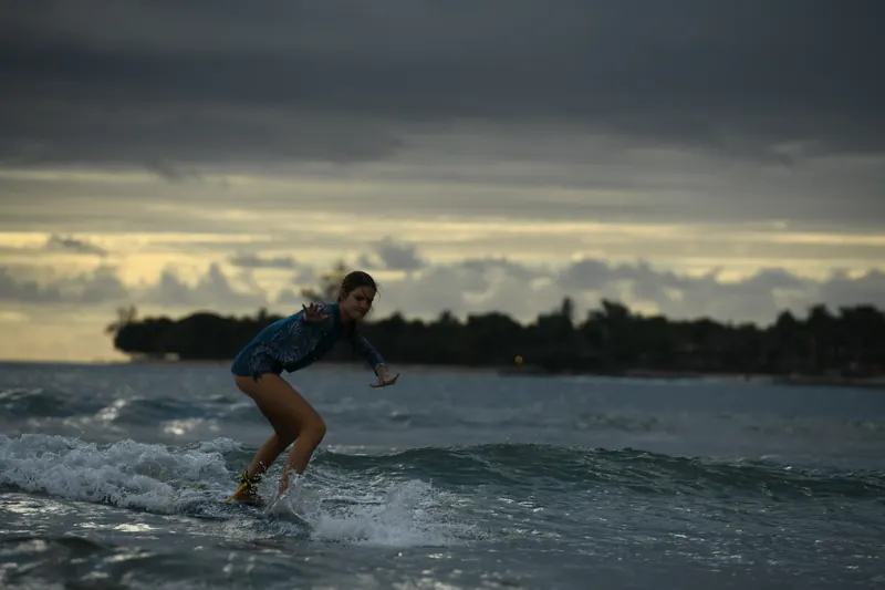 The Final at sunset: a Duckie riding a wave in silhouette under a dramatic sky.