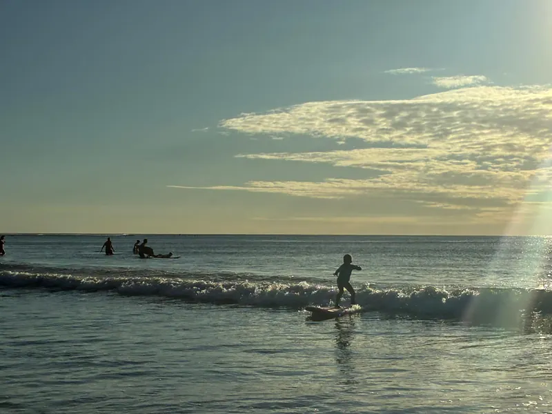 Evening glide across a glassy wave, sun rays on the water.