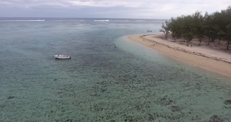 The sandy point at Le Morne from above: turquoise lagoon, filao trees and a small boat.
