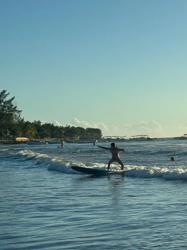 Riding a wave along the shore, filao trees behind.