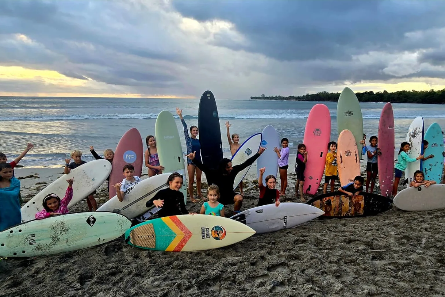 The Sunset Duckies crew with their boards on Tamarin beach at dusk.